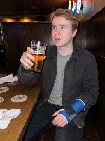 Kingston, AI character: a quiet Milwaukee corner bar after a Brewers game, dark wood booths and beer signs behind him