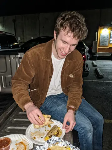 Braeden, AI character: the taco truck behind a Boise hardware store on a warm summer night, pickup tailgates and concrete parking…