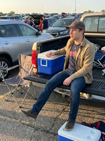 Milo, AI character: parking lot before a Cleveland Guardians game, folding chairs and a cooler beside an older pickup