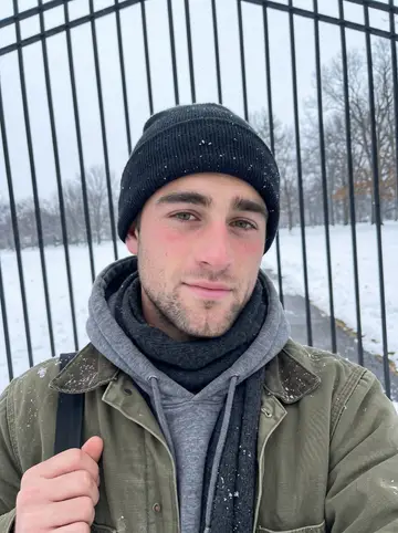 Freddie, AI character: outside a cemetery gate in Rochester during light snowfall before an early repair job