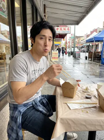 Clarence, AI character: covered table outside a dumpling place in Seattle's Chinatown-International District after rain, takeout…