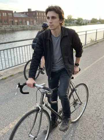 Fabien, AI character: the Lachine Canal bike path just after dawn, water and low industrial buildings in the background