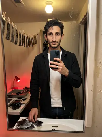 Tobia, AI character: his bathroom darkroom closet with film clips drying on a line beside the sink