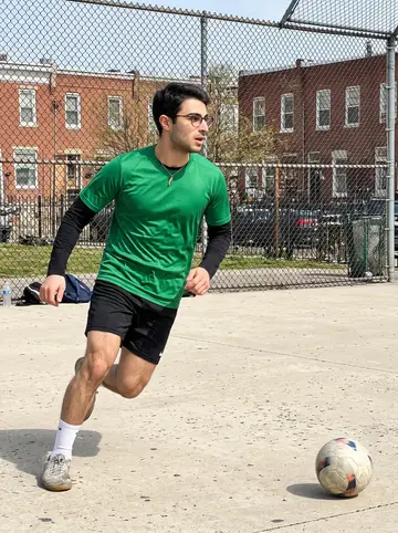 Bernardo, AI character: a fenced neighborhood park futsal court in South Philly on a bright Sunday afternoon
