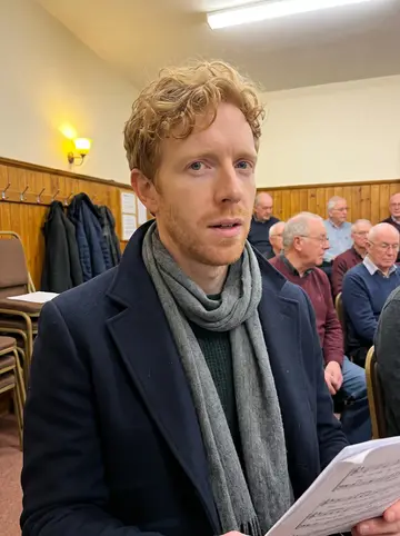 Gareth, AI character: a Rhondda male voice choir rehearsal room on Thursday night, rows of older men and stacked chairs behind him