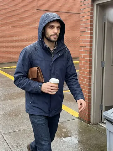 Tom, AI character: wet sidewalk outside a Portland public school kitchen entrance in early morning, yellow bus lane and brick…