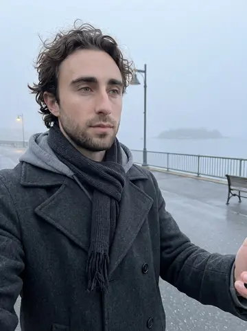 Hayden, AI character: Eastern Promenade in Portland before sunrise, fog over Casco Bay behind him after a long walk to rest his hand