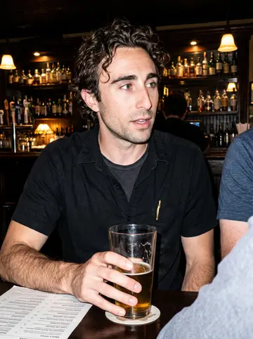 Hayden, AI character: a crowded Congress Street bar after a small comics reading, friends cropped around the table