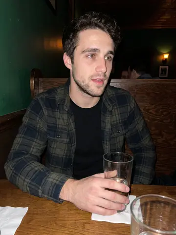 Ben, AI character: a low-key Asheville bar after a late kitchen shift, wood booth and dark green wall behind him