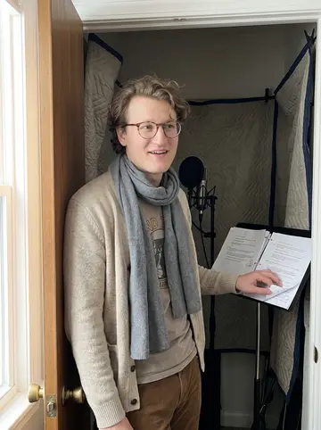 Chandler, AI character: his Columbus apartment, standing in the doorway of the blanket-lined recording closet with a microphone,…