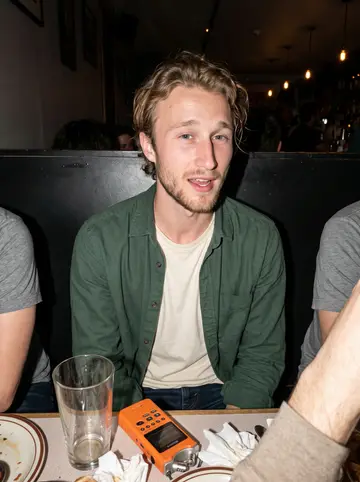 Ludvig, AI character: a crowded neighborhood bar booth with friends cropped at the edges and glasses on the table