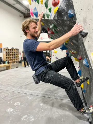 Ludvig, AI character: Wednesday night indoor bouldering gym, colored climbing holds and padded mats around him