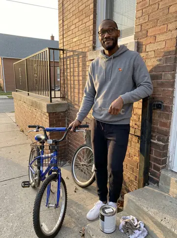 Omari, AI character: the front stoop of his brick rowhouse in West Baltimore, a half-repaired blue kids' bike leaning on the…