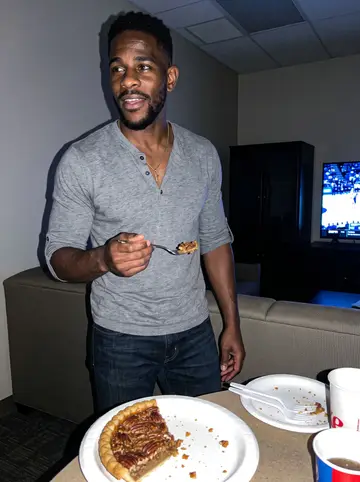 DeShawn, AI character: the fire station dayroom at night during a Grizzlies game on TV, paper plates and pie slices on the table
