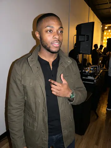 Babatunde, AI character: a small Afrobeats DJ night in Atlanta, standing near the edge of the dance floor while his uncle works the…