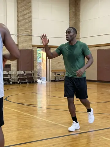 Junior, AI character: Tuesday night pickup basketball at a church gym on Detroit's east side, glossy wood floor and folding…