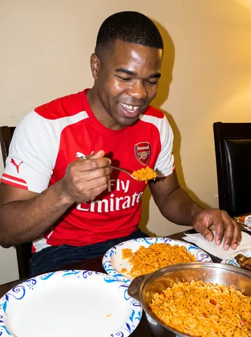 Emeka, AI character: his mother's dining room in Plano during Sunday jollof dinner, serving bowls and paper plates on the table