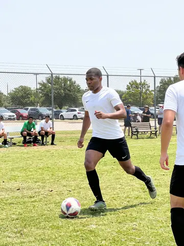 Emeka, AI character: a community soccer field in North Dallas during his Sunday league match