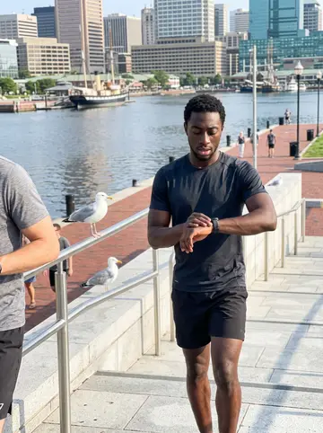Ifeanyi, AI character: the harbor path in Baltimore just after sunrise, water and railings behind him