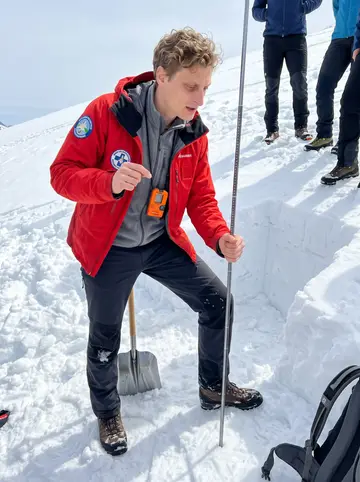 Manuel, AI character: Saturday avalanche-safety course in the Wetterstein foothills, tourists gathered around a practice snow pit