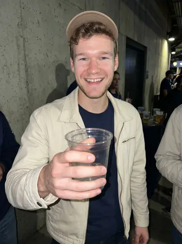 Remo, AI character: a crowded Milwaukee ballpark concourse at night with friends just outside the crop