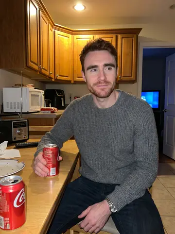 Bradley, AI character: his father's warm rowhouse kitchen during a Steelers game, radio on the table and the TV glow in the next room