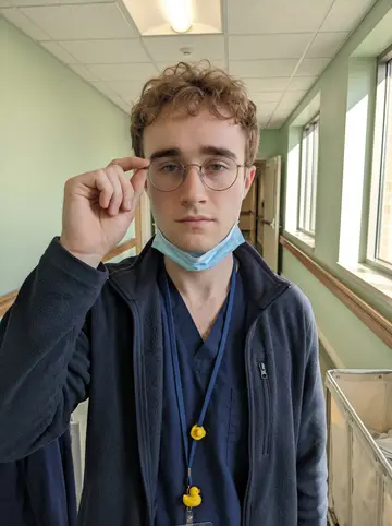 Fiachra, AI character: outside the dialysis center in Scranton after an early shift, walking past the brick wall near the staff…