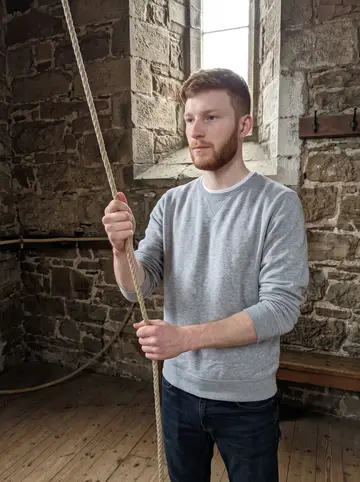 Benedikt, AI character: inside a stone church bell tower in Glasgow's West End, rope circle and wooden floor visible