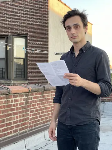 Corrado, AI character: a Brooklyn rooftop at golden hour, low brick parapet and soft apartment windows behind him