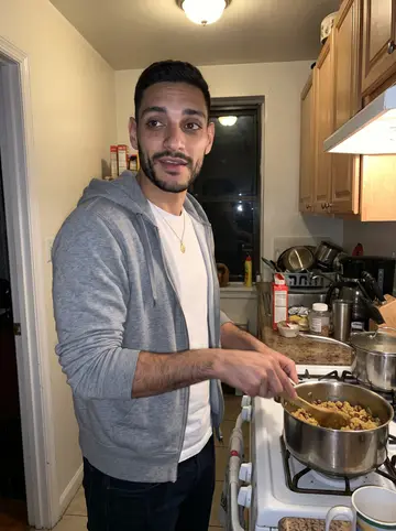 Rogelio, AI character: his abuela's small Bronx apartment kitchen at night, sauce pot on the stove and a crowded counter behind him