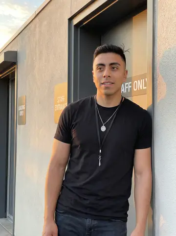 Eduardo, AI character: outside the Phoenix concert venue by the staff entrance just before doors open, warm desert light on the…