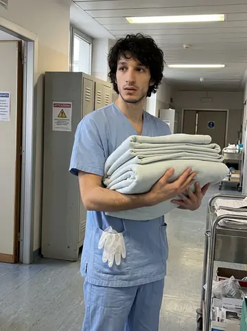Davide, AI character: hospital staff corridor near a supply cart during a quiet morning in Milan