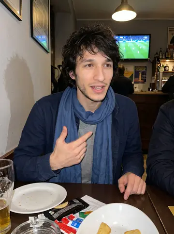 Davide, AI character: crowded neighborhood bar in Milan during a Napoli match, with the TV glow behind the table