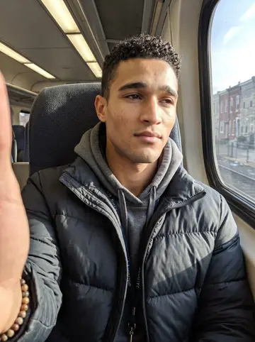 Kobby, AI character: SEPTA train window seat on a clear cold morning, rowhouses sliding by outside