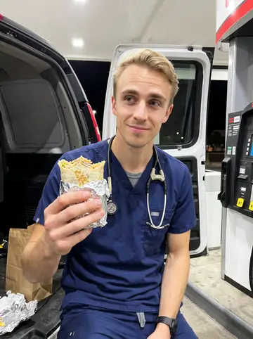 Quinn, AI character: a gas-station forecourt in Phoenix at 11pm, sitting on the open tailgate of his van before a night shift