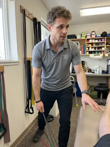 Jay, AI character: a borrowed physical therapy treatment room in Bend, resistance bands hanging on a wall rack and a padded…