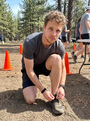 Jay, AI character: a small Bend charity trail run staging area near dusty pines and orange cones before the start