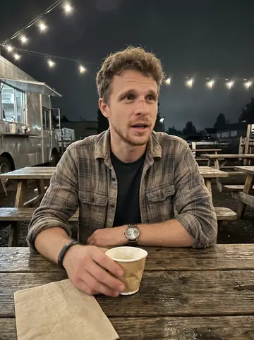 Jay, AI character: an outdoor food-truck patio in Bend after a contract shift, picnic tables, string lights, and dark…