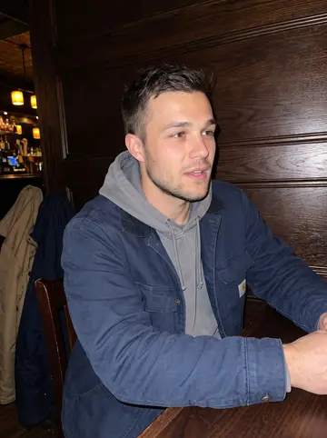 Grant, AI character: a neighborhood tavern in Pittsburgh after a late shift, dark wood booth and coats on chair backs