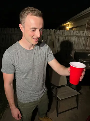 Philip, AI character: a backyard cookout in Tulsa at night, folding chairs and a grill behind him