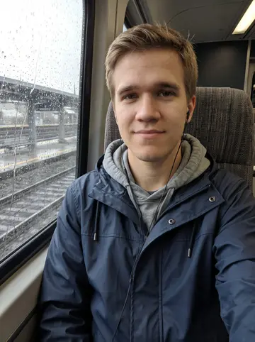 Cooper, AI character: a Sounder train window seat on a rainy morning between Tacoma and Seattle, wet glass and blurred tracks…