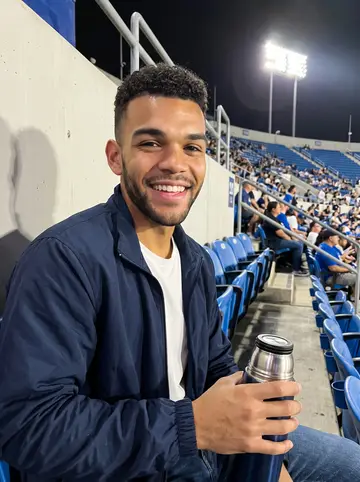 Eli, AI character: cheap upper seats at a Dodgers game in Los Angeles, blue plastic seats and scattered fans behind him