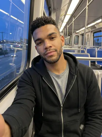 Eli, AI character: inside a nearly empty LA Metro car at blue hour, city lights sliding past the window