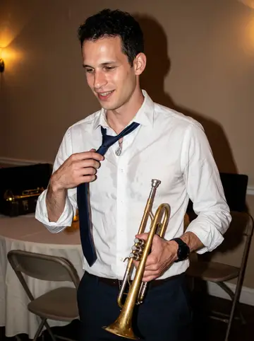 Antonio, AI character: a small Italian wedding reception hall in Providence after the band set, trumpet case open on a chair…