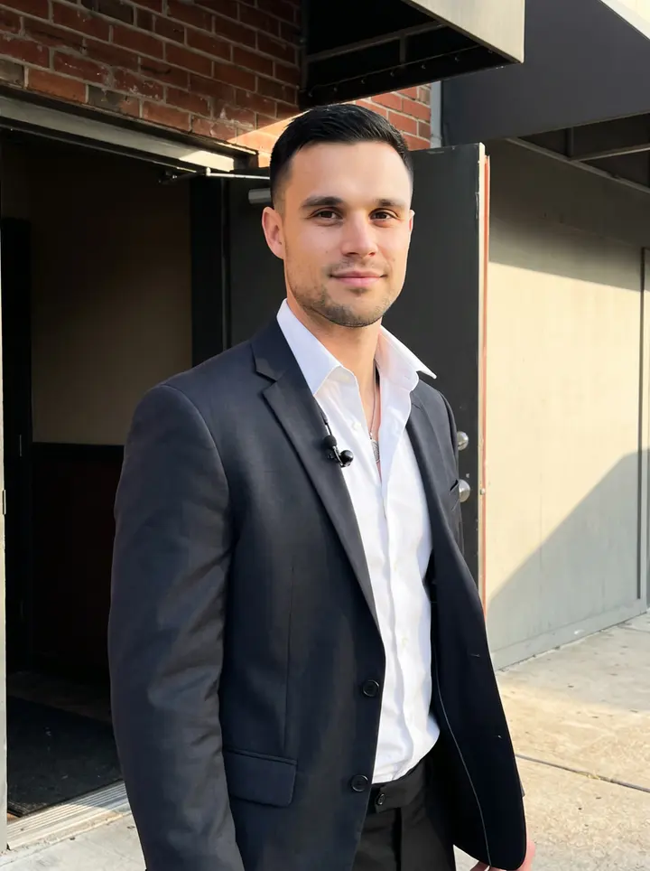 Maxwell, AI character: outside the side entrance of the Houston club before his shift, brick wall and dark doorway behind him