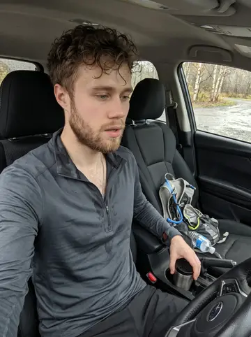 Joonas, AI character: outside the Duluth police station by the parking lot during a gray afternoon shift break