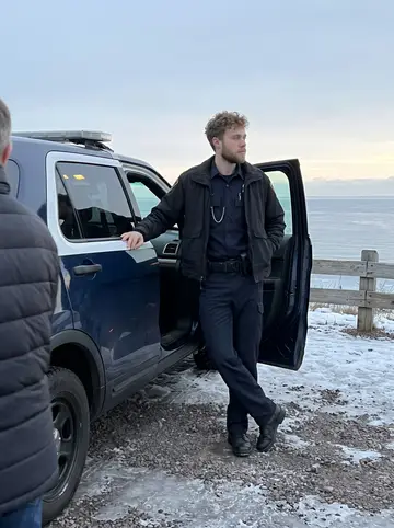 Joonas, AI character: a snowy overlook on the North Shore just after a night shift, his old car parked beside the road
