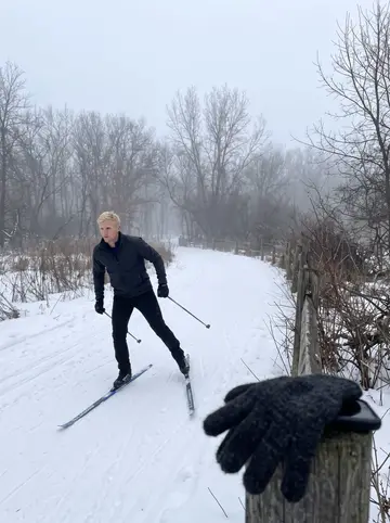 Jeppe, AI character: a quiet cross-country ski trail outside Minneapolis in early morning fog, the phone propped on a fence…