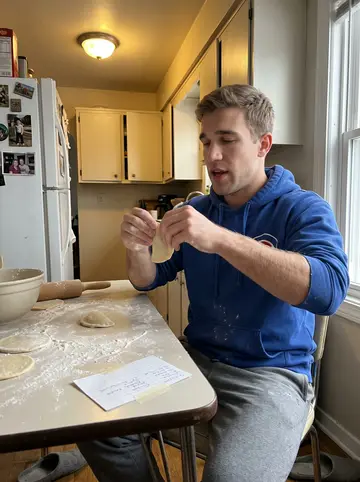 Marek, AI character: his grandfather's small kitchen in Avondale on a Sunday afternoon, a floured table with rounds of pierogi…