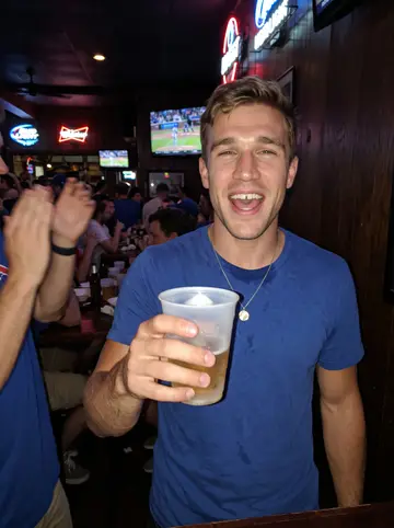 Marek, AI character: a crowded neighborhood sports bar near Wrigleyville during a Cubs game, a TV and a neon beer sign behind him